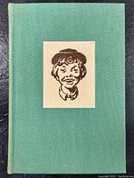 Front cover of vintage hardcover book with green cloth and a portrait sketch of a boy on white rectangle in the center.