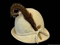 Front left angle view of the vintage white hat with tall feather showing texture and decorative band.