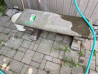 Full view of bench seat and supports on paved surface