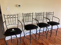 Four metal counter height stools lined up against wall