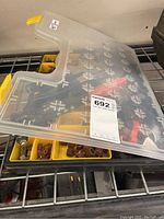 Dremel rotary tool set in plastic case with various sanding attachments and the punch tools laid near and underneath case.