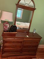 Front view of the dresser with lamp and fan on top, mirror mounted behind.