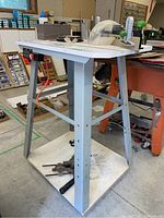 Full view of the Haussmann work table on metal swivel platform base, showing metal legs and work surface with tools.
