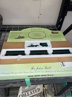 Photo of HO scale John Bull model train set in original styrofoam packaging showing locomotive, tender, and three coaches.