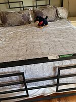 Black metal footboard with striped mattress and pillows, plush dog toy on top