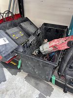 Photo showing the Milwaukee drill placed inside the black toolbox along with bits and screwdrivers, toolbox is open and shows signs of wear.
