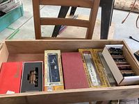 Top view of a wooden drawer containing boxed model rail cars of various brands and styles, including a visible log car in red box and others in yellow and white packaging.