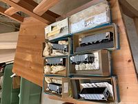 Six Athearn HO scale model train cars displayed in original blue and white boxes with tissue packaging on a wooden surface.