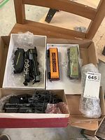 Overview showing two black locomotive engines/parts in boxes and two boxcars in white box.