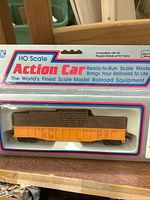 Photo of HO scale INC Action Car boxcar in original packaging with orange body and brown cargo load