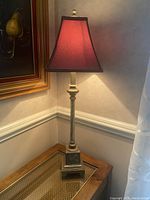 Buffet lamp placed on a corner table, showing the brushed gold base and the burgundy-gold fabric shade lit from within.