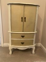 Front view of the small cabinet showing two drawers and two cabinet doors with bronze handles.