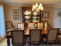 View of dining room showing Ethan Allen china cabinet with burl wood accents and matching dining table and chairs, dishes displayed inside the cabinet.