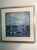 Full view of framed lake scene art depicting water and two canoes, with white mat and silver frame.