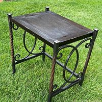 Front angled view of the metal and wood accent table showing the decorative twisted and scroll metal sides and dark wood top.