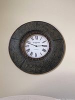 Front view of the large round Rutherford wall clock showing carved wood frame and Roman numeral clock face