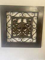 Square wall art with an oil-rubbed bronze wooden frame and ornate metal urn centerpiece with scrollwork.