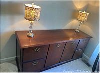 Solid wood credenza with detailed wood trim and brass hardware. Top is clear and polished, showing minimal surface wear. Four file drawers on the left and right sides, with two cabinet doors in the center providing additional storage.