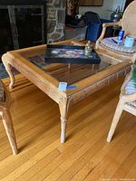 Full view of square wooden coffee table with glass top showing carved legs and part of the living room setting.