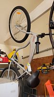 Full side view of the Coors Light branded silver bicycle hanging in a garage showing the frame, rear tire, and seat