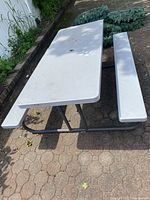 Full view of white Lifetime picnic table with two attached benches on a paved surface outdoors