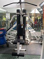 Front view of Para Body multi-exercise gym machine with padded seat and backrest, dual arms for exercises, and black weight stack behind.