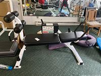 Side view of exercise bench showing padded seat, adjustable handle, and leg rollers with weight plate attached.