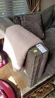 Front and side view of sofa armrest showing nailhead trim and matching pillows with fabric detail.