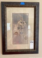 Framed floral wall art showing a single large flower and leaves in muted tones with an ornate dark wood frame.