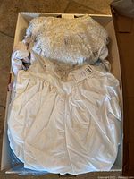 Full view of vintage 1980s ivory wedding dress with puffed sleeves and gathered skirt inside a box.