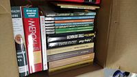 Box of books showing health, medical, poetry, writing, and wildlife titles stacked lying flat.