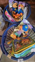 Two blue plastic laundry baskets filled with Disney new in box plush toys and Disney-themed lunch bags.