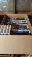 Box of multiple VHS tapes, arranged side by side, showing a mix of Disney and family movie titles.