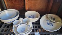 Full set arranged on a shelf showing bowls, lidded platter, and salt and pepper shakers with blue floral motifs.