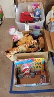View of the lot with bins containing assorted stuffed animals, Dr. Seuss books and posters, and toy cars and kits.