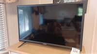 Front view of the Vizio LCD television showing the black screen, slim bezel, and the stand on a wooden surface in a well-lit room.