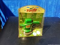 Front view of Turtle Wax 6 inch Electric Random Orbit Waxer/Polisher in sealed retail packaging, showing green tool and Turtle Wax branding.
