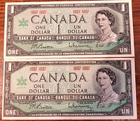 Front side of two 1967 Canadian Centennial one dollar bills showing Queen Elizabeth II and centennial dates