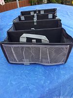 Front view of the black heavy cloth trunk organizer showing the mesh pocket on one end and the 4 compartment dividers inside.