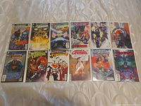 Lot of 12 mint condition DC Comics, carded and bagged, arranged on a bedspread showing front covers.