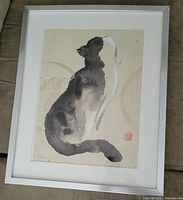 Framed artwork showing a gray and white cat sitting in a minimalist ink wash style with visible framing and matting.