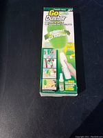 Front view of Go Duster box showing product and features including motorized spinning duster and bonus microfiber spray.