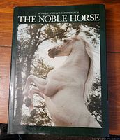 Front cover of a large hardcover coffee table book titled 'The Noble Horse' with a rearing white horse on the cover.