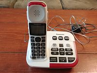 Panasonic cordless phone handset placed on base with cords visible, showing the full device in working condition.