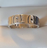 Close-up photo of the outside of the silver band ring showing the etched pattern with oval shapes and dots.