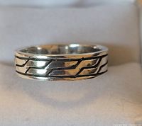 Close-up front view of sterling silver ring band showing the etched linear pattern.