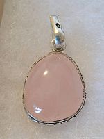 Close-up photo of a teardrop-shaped rose quartz pendant set in sterling silver with .925 marking on the bail