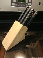 Wooden knife block with six knives inserted, showing block and knife handles