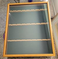 Top view of rectangular wooden display case with glass cover, showing internal slots for holding items and hook on back for hanging
