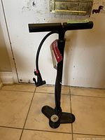 Full view of the black Blackburn Piston 1 floor pump with handle, hose, and gauge on floor
